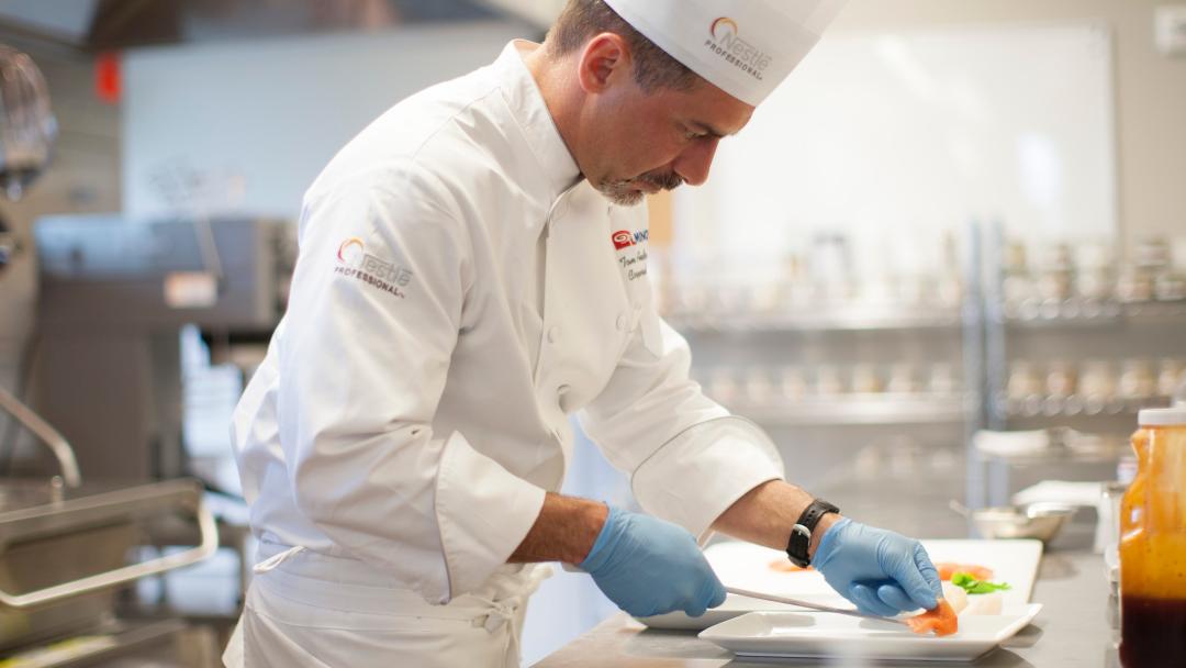 Chef Thomas Andresakes plating a dish in the kitchen